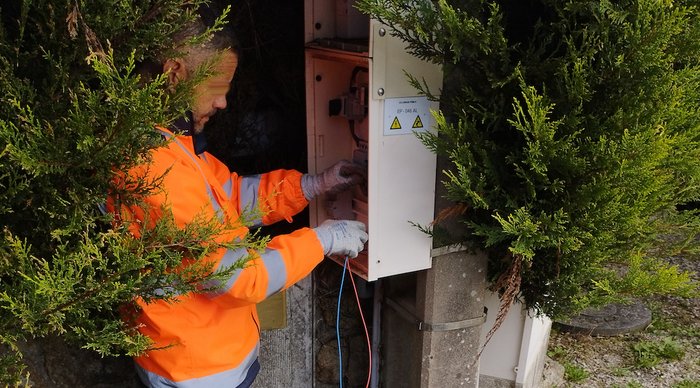 Homme installant une horloge connectée dans une armoire d’éclairage public à Crac’h